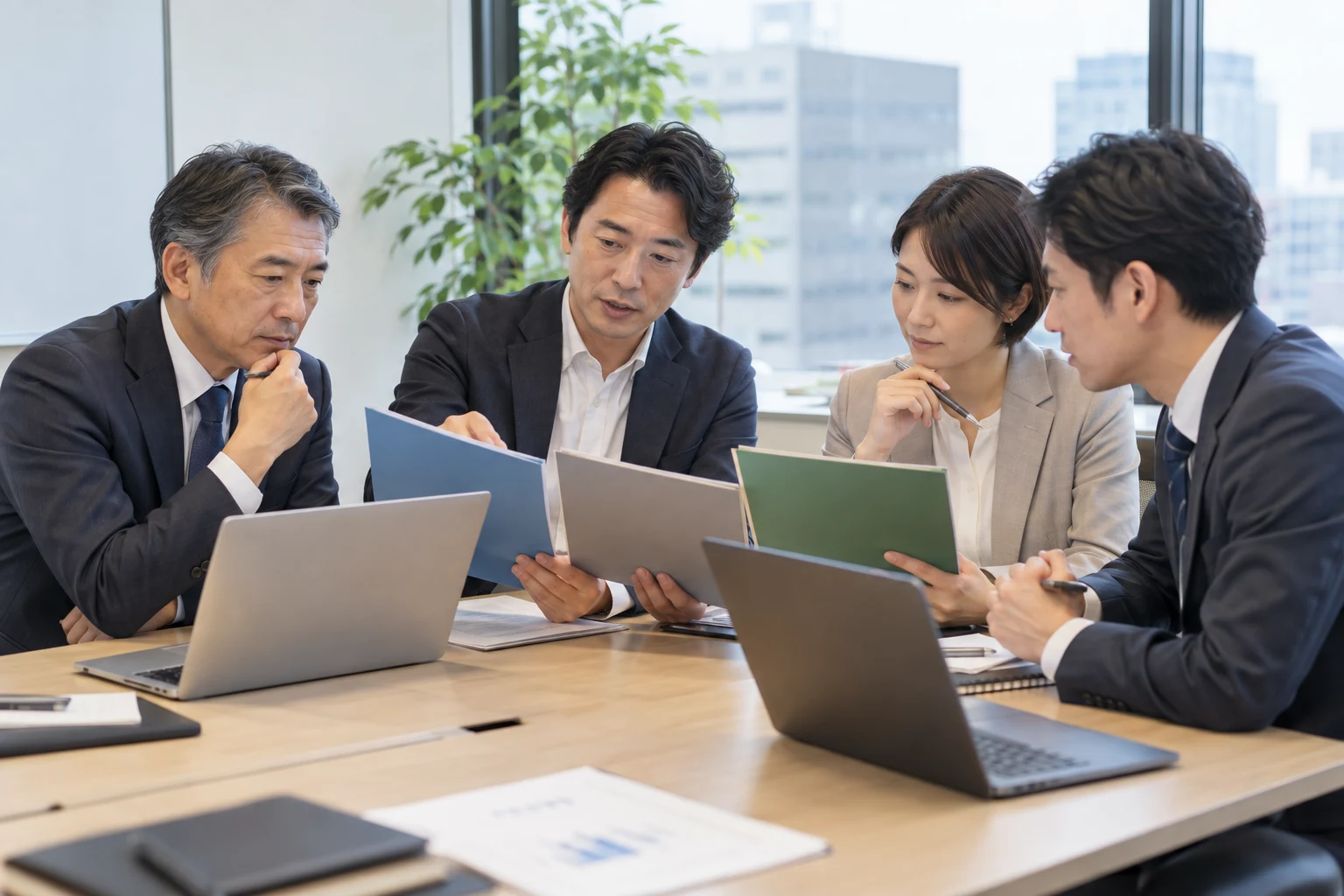 経営者と支援担当者が、複数ベンダーの提案資料を比較・検討する様子