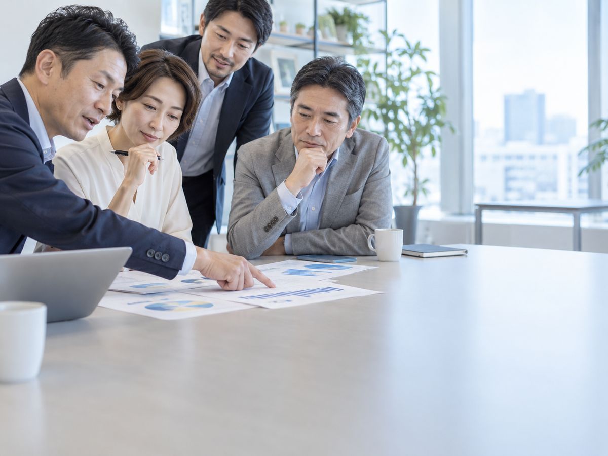 資料を指し示しながら話し合う経営陣