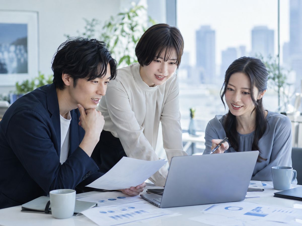 資料とノートPCで計画を話し合うチーム